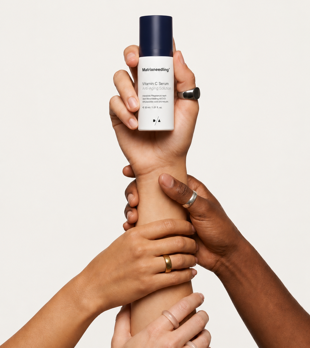 Diverse hands holding a serum bottle together